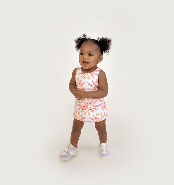 Ka’lani wears a size 12-18M in the Orange Shell Mosaic Cotton color: Orange Shell Mosaic Cotton